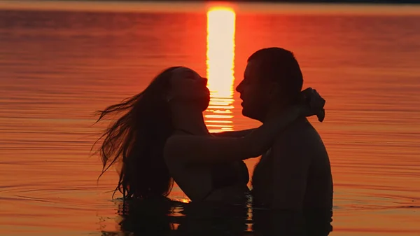 Mädchen und Junge schwimmen bei Sonnenuntergang — Stockfoto