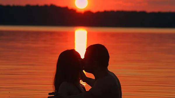 Bacio romantico in acqua su uno sfondo tramonto — Foto Stock