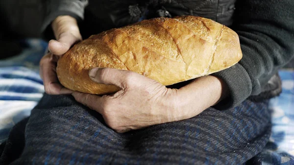 Nonna mani che tengono una pagnotta marrone di pane — Foto Stock