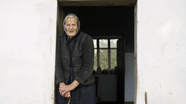 Old grandmother on a background of an old house — Stock Photo, Image