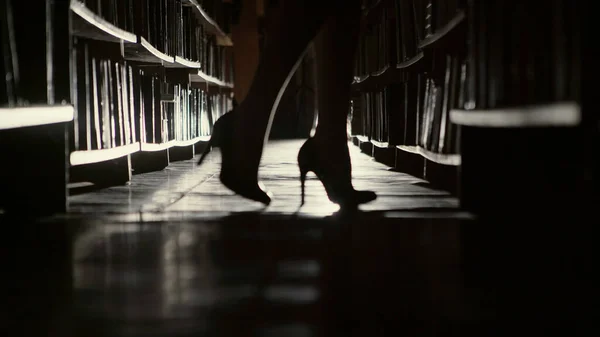 Hermoso bibliotecario va a lo largo de las filas de libros en las bibliotecas — Foto de Stock