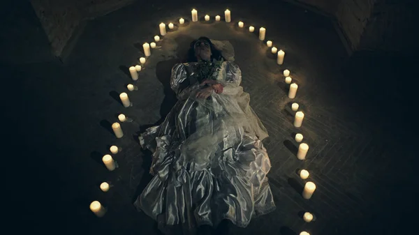 Sorrow scene of a corpse bride on the floor like a ritual with candles