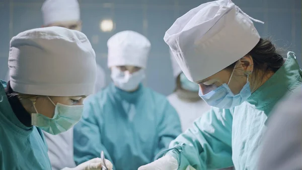 Grupo de cirurgiões concentrados vestindo uniforme na sala de cirurgia — Fotografia de Stock