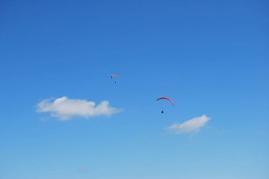 Mavi bir gökyüzünde güzel bir paraglider. Paraglider üzerinde uçan sporcu, havada ekstrem sporlar