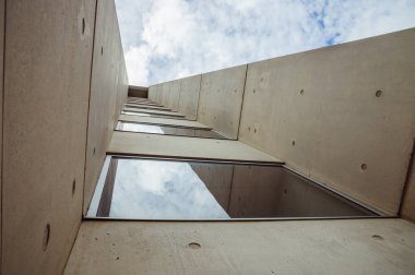 Modern bir beton binanın güzel mimarisi fiberglas, mavi bulutlu gökyüzü manzaralı.