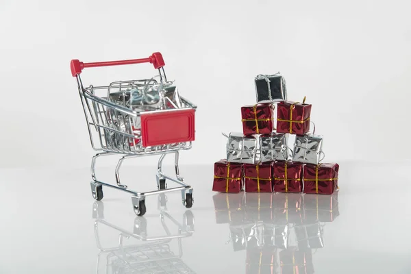 Composición de fondo de compras navideñas de múltiples bolas de decoración y pequeño carrito de compras sobre la superficie de madera Imagen De Stock