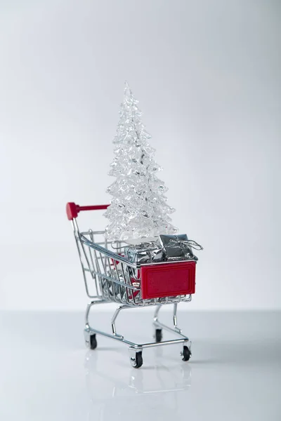 Composición de fondo de compras navideñas de múltiples bolas de decoración y pequeño carrito de compras sobre la superficie de madera Imagen De Stock