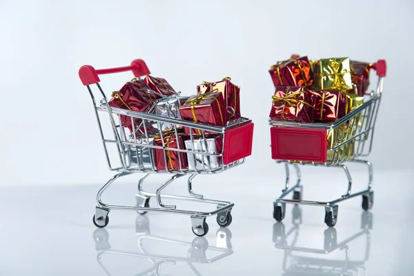 Composición de fondo de compras navideñas de múltiples bolas de decoración y pequeño carrito de compras sobre la superficie de madera Fotos De Stock Sin Royalties Gratis