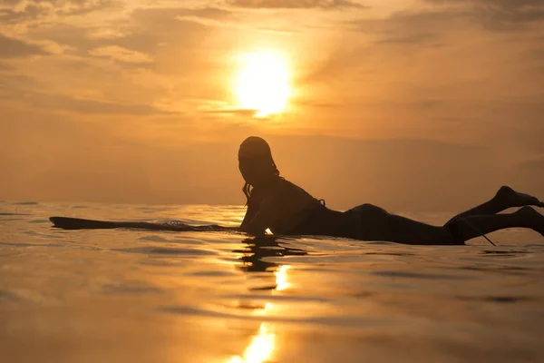 Surfer girl in ocean at sunset time — Stock Photo, Image