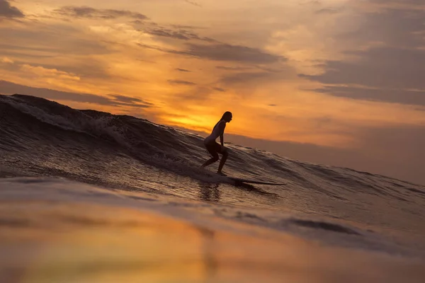 Surfer κορίτσι στον ωκεανό κατά το ηλιοβασίλεμα — Φωτογραφία Αρχείου
