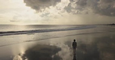 Kumsalda yürüyen bir kadının hava manzarası.