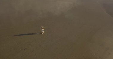 Kumsalda yürüyen bir kadının hava manzarası.