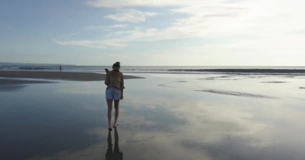 Luftaufnahme einer jungen Frau, die am Strand spaziert — Stockvideo