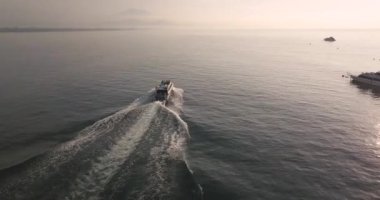 Güneş doğarken arka planda kayık ve volkan manzarası.