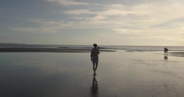 Vista aérea da jovem caminhando na praia ao pôr do sol — Vídeo de Stock