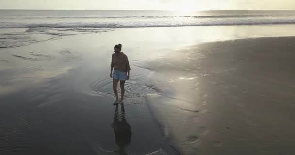 日落时分在海滩散步的年轻女子的空中照片 — 图库视频影像