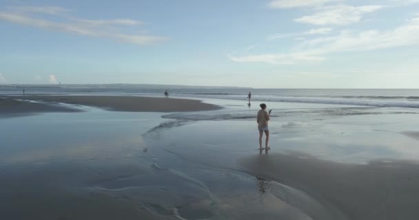 Vista aérea da jovem caminhando na praia ao pôr do sol — Vídeo de Stock