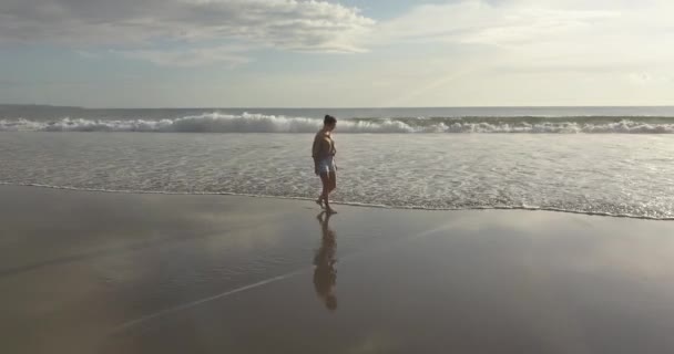 Αεροφωτογραφία της νεαρής γυναίκας που περπατάει στην παραλία το ηλιοβασίλεμα — Αρχείο Βίντεο