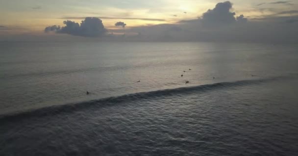 Vista aérea dos surfistas no oceano ao pôr-do-sol — Vídeo de Stock