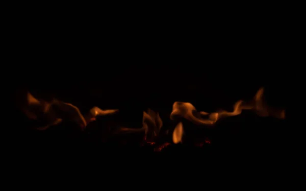 Orangefarbene Flammen breiten sich aus aus der Schwärze — Stockfoto
