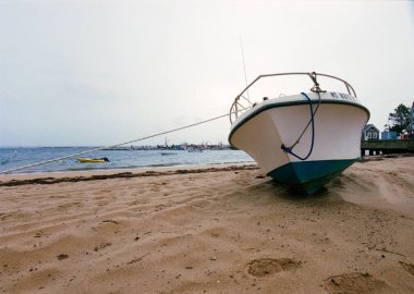 Deniz kıyısında kumlu bir sahilde karaya vurmuş bir tekne.