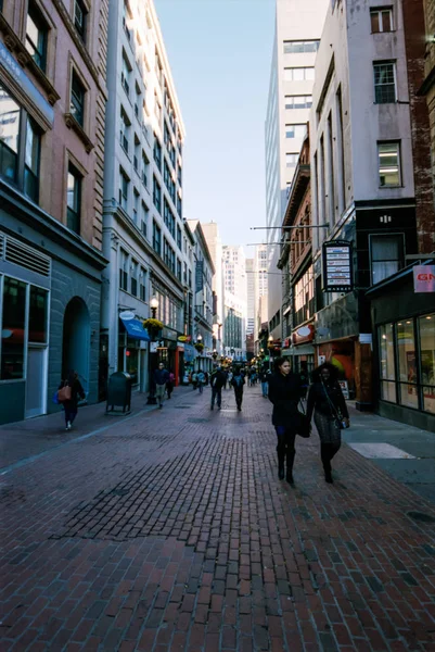 Mensen lopen langs een voetgangersstraat met winkels aan weerszijden. — Stockfoto