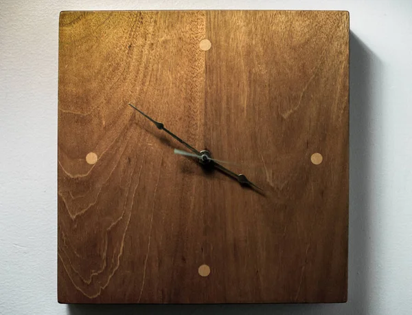 Eine Holzuhr vor einer weißen Wand — Stockfoto