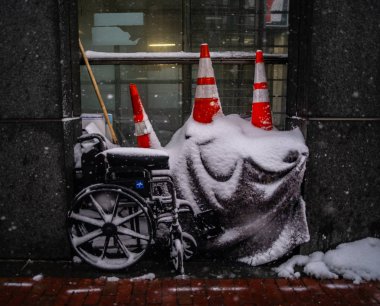 Cones Atop a Wheelchair and Tarp Along a Sidewalk clipart