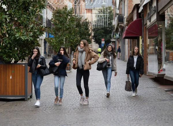 Öt lány sétál át a városon, miközben a hidegben vásárolnak. Stock Kép