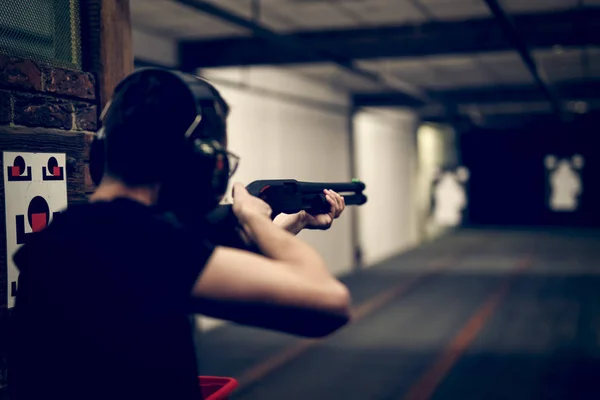 Homem atirando na faixa de tiro interior — Fotografia de Stock