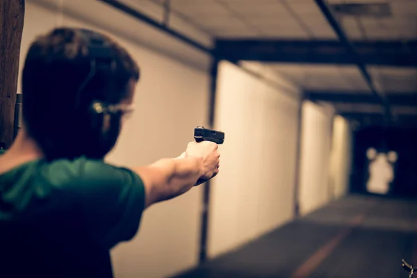 Muž střílí v kryté střelnice — Stock fotografie