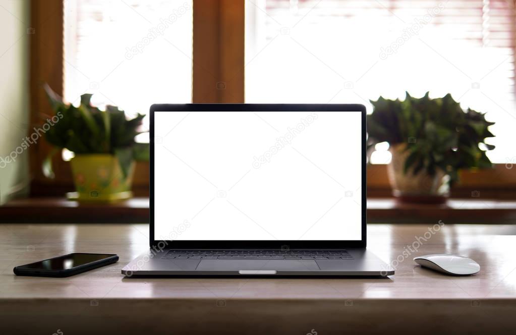 Laptop with blank screen on table in home interior