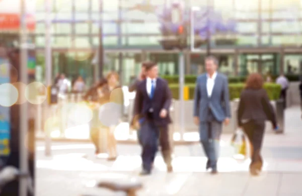 Gente de negocios caminando por la ciudad, imagen borrosa con reflejo de luces. Concepto de negocio y vida moderna — Foto de Stock