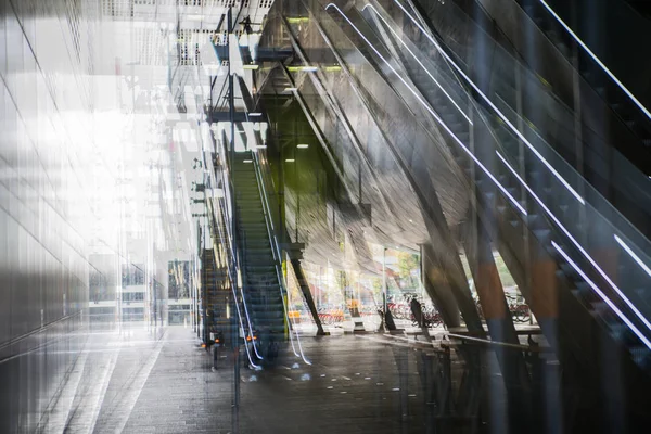 Architettura moderna, stazione ferroviaria con scale mobili, travi metalliche di supporto, biglietteria automatica. Immagine a esposizione multipla — Foto Stock