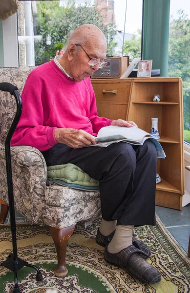 95 years old English man sitting in chair in domestic environment. Health and care concept