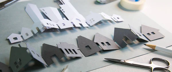 Paper cut design elements with tools: scissors, knife, pare, glue etc. Creation a city view in progress. Creativity, education, hobby, innovation and inspiration concept.