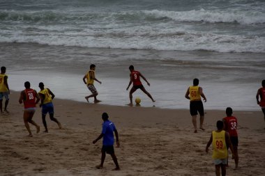 Hafta sonu sporcusu plajda futbol oynuyor.