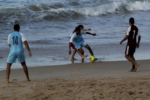 Hafta sonu sporcusu plajda futbol oynuyor.
