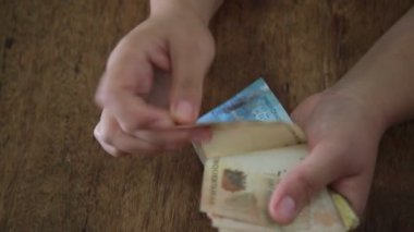 Salvador, Bahia / Brezilya - 28 Mart 2020: Brezilya 'da kullanılan para birimi olan Reais banknotları kadının ellerinde..