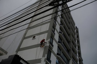 Salvador, Bahia / Brezilya - 8 Temmuz 2016: Salvador kentindeki Pituba mahallesindeki resim çalışmaları sırasında bir binada asılı duran adam görülüyor