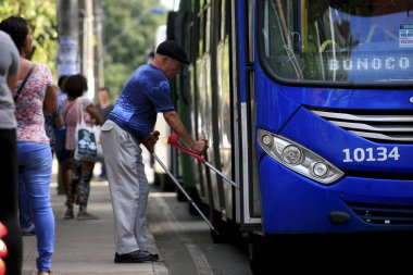 Salvador, Bahia / Brezilya - 8 Temmuz 2016: Sınırlı hareket kabiliyetine sahip yaşlı bir adam Salvador 'daki Avenida Tancredo Neves otobüs durağında otobüse biniyor.