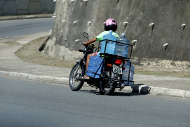 Salvador, Bahia / Brezilya - 6 Nisan 2017: Salvador şehrinde Avenida Luiz Viana 'da motorsikletle maden suyu teslimatı
