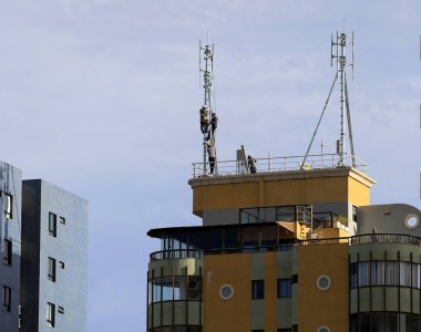 Salvador, Bahia / Brezilya - 15 Mart 2018: İşçiler, Salvador kentindeki Armacao mahallesindeki bir inşaat terasında cep telefonu antenleri üzerinde çalışırken görülüyor. 