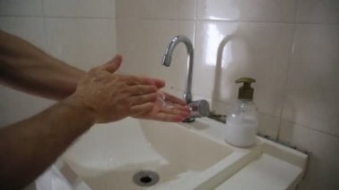Salvador, Bahia / Brezilya - 12 Mayıs 2020: Salvador şehrinde banyo lavabosunda ellerini yıkayan kişi görülüyor..