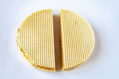 Beyaz arka planda kaynamış yoğunlaştırılmış sütle iki parça waffle keki. Bir şeyi ikiye bölme kavramı.