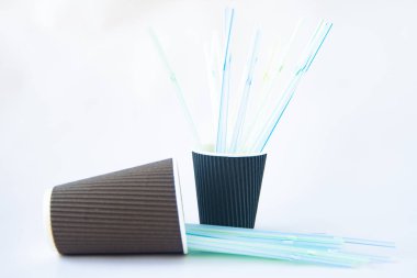 Beyaz arka planda bir sürü plastik pipet olan büyük ve küçük kahverengi kağıt bardaklar. Geri dönüşüm, çöp, kafelerden gelen çöpler, sıfır atık, çevrenin desteği.