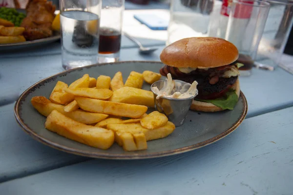 A delicious burger with chips on a plate.