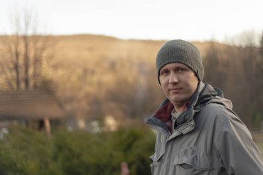 Dağların arka planında, sıcak kış örtüsü içinde genç bir adamın portresi..