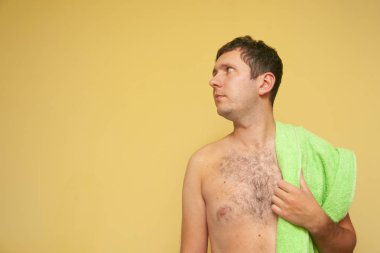 Sırtında yeşil havluyla genç bir adam. Yüzmeye, banyo yapmaya, dinlenmeye, banyo yapmaya hazır olma kavramı.