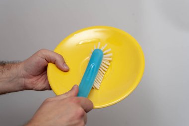 The man's hands are cleaning up by dish brush on a white background.